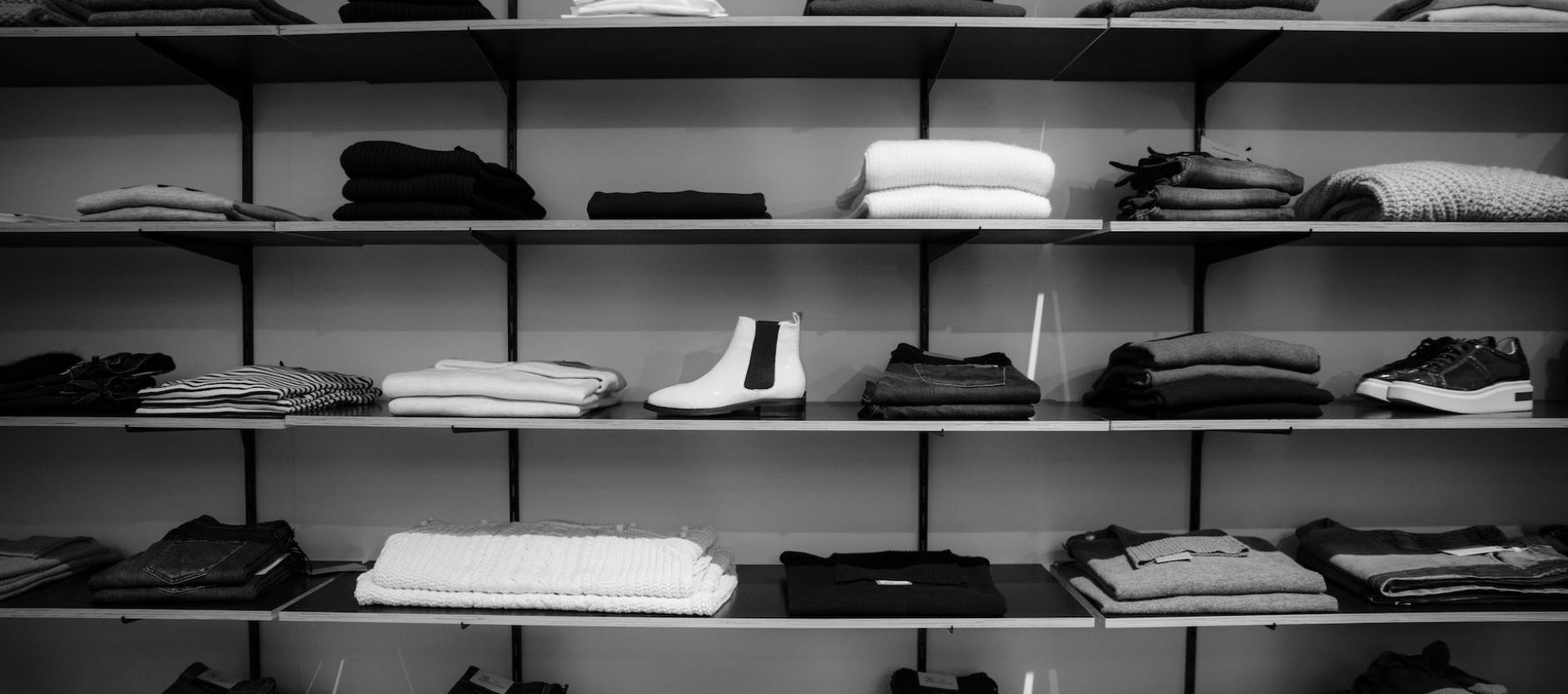 grayscale photography of assorted apparels on shelf rack